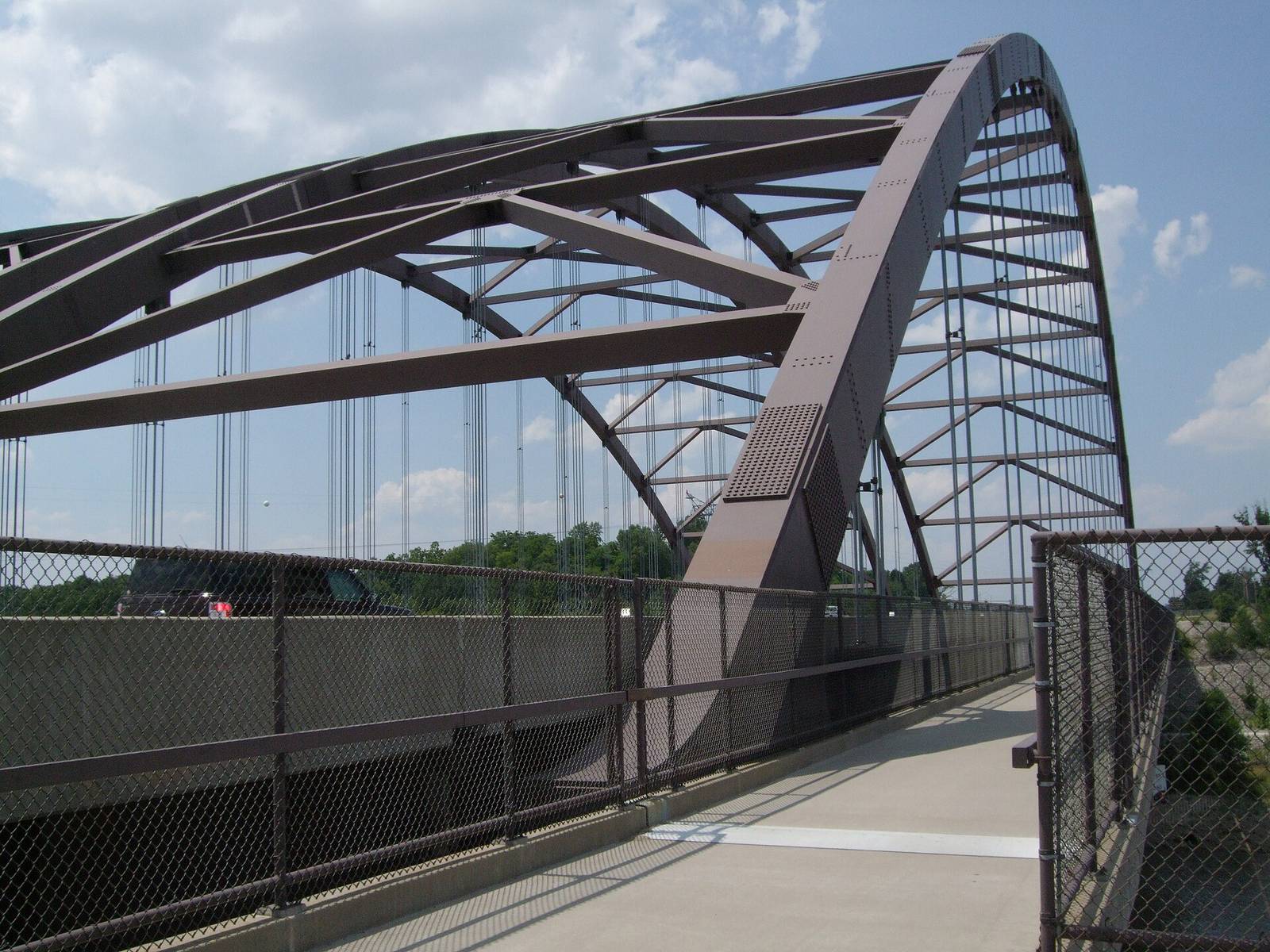 The steel arch of the Route 364 bridge over the Missouri River, seen from the pedestrian path along the deck on a bright summer day